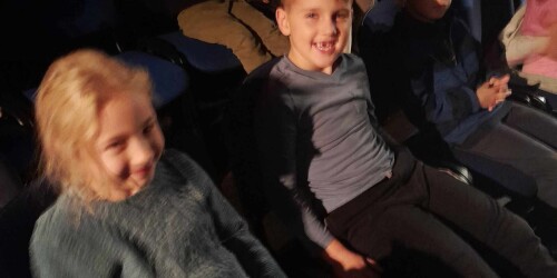 dzieci siedzą na widowni w teatrze